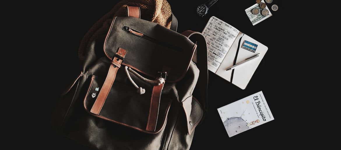 A travel essential brown backpack sitting on top of a table.