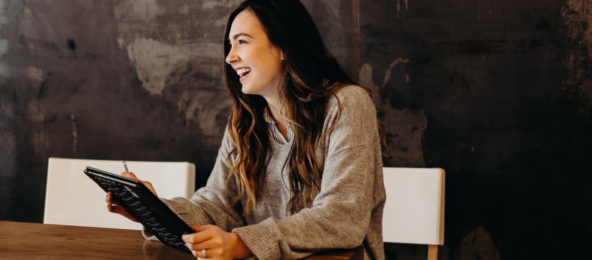 A woman participating in a remote work interview is seen holding a tablet.