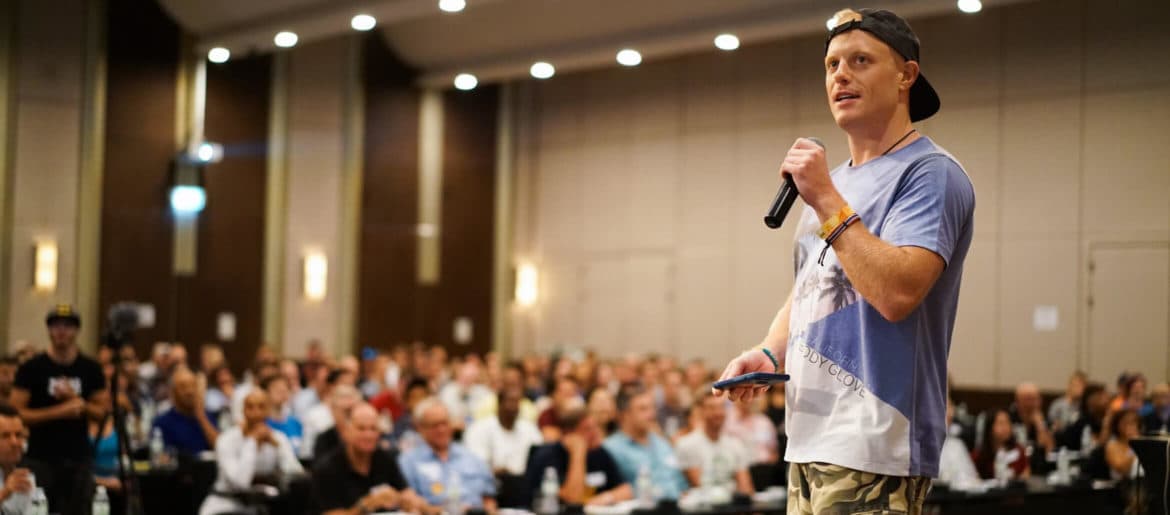 A man holding a microphone in front of a crowd at an event.