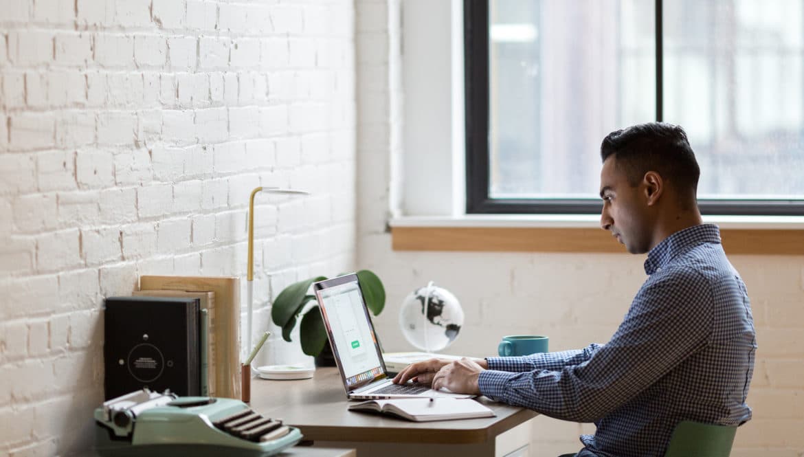 a man sitting at a desk working on a laptop.