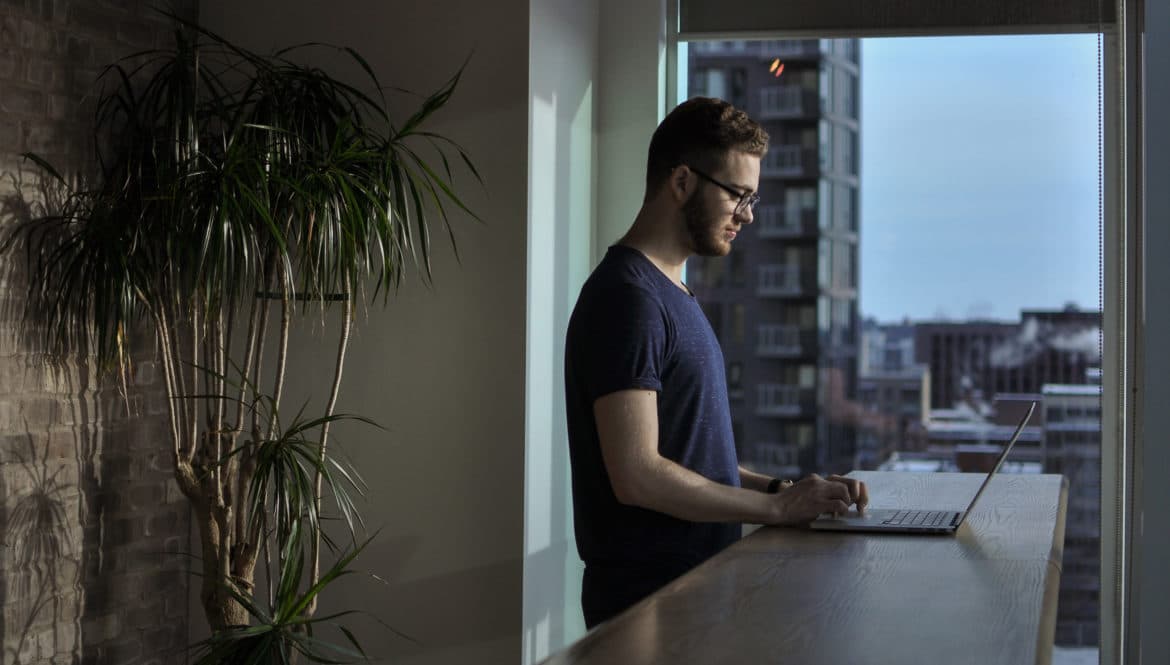 a man in a blue shirt is using a laptop.