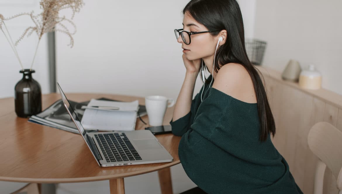 a woman sitting at a table with a laptop.