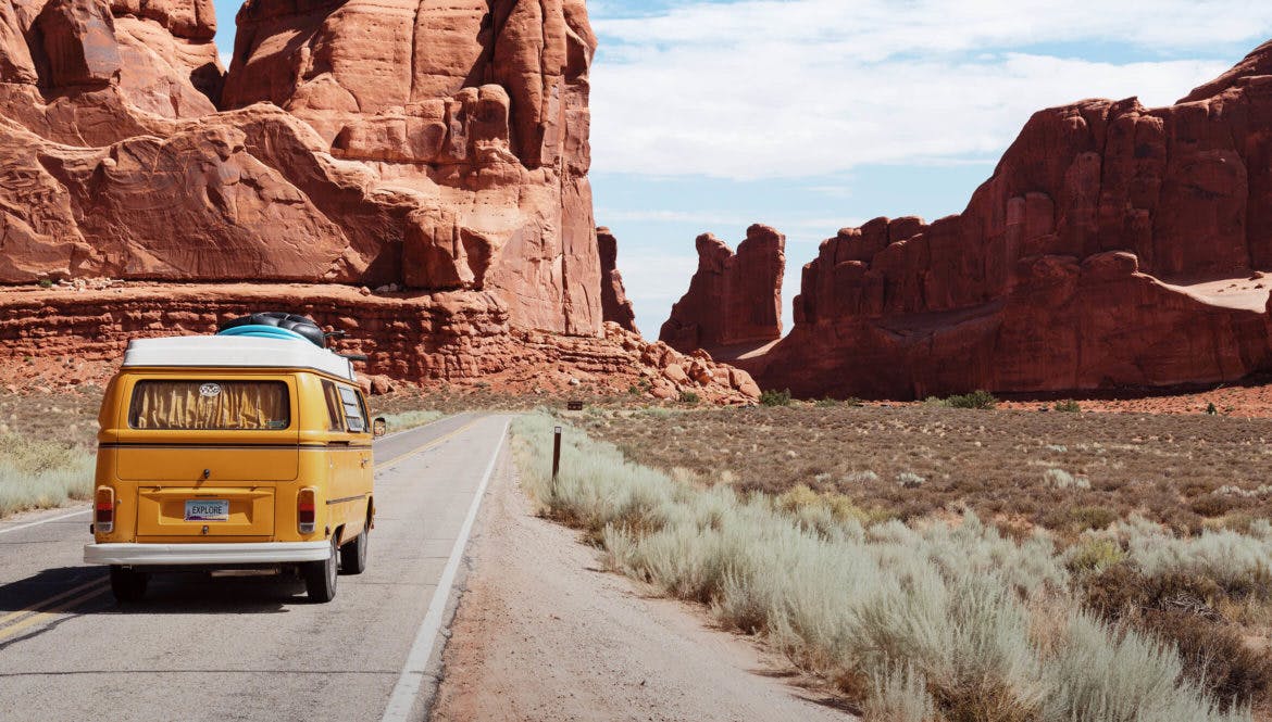 A nomad driving a yellow van down a desert road.