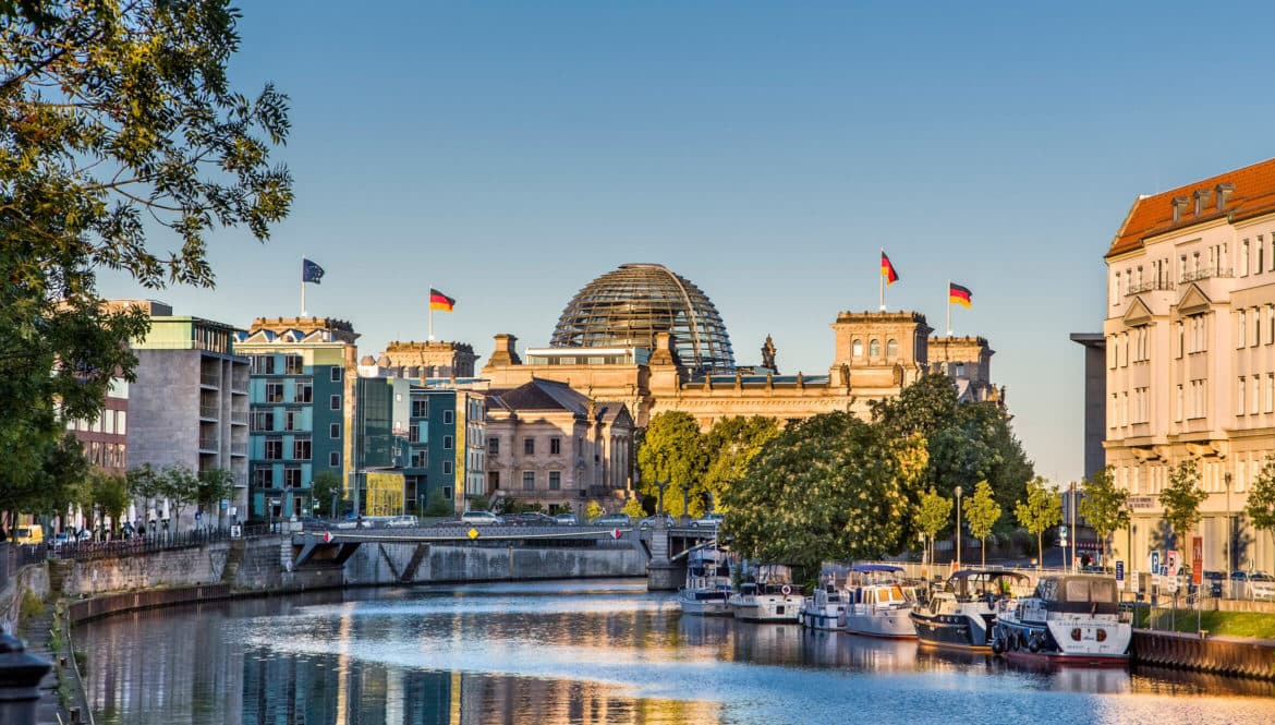 A river running through Berlin next to tall buildings, making it an ideal location for digital nomads.