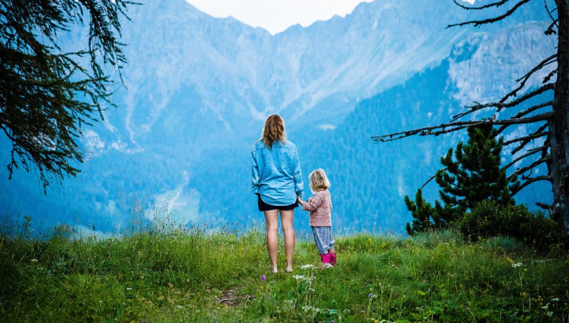 A digital nomad family standing on top of a lush green hillside.