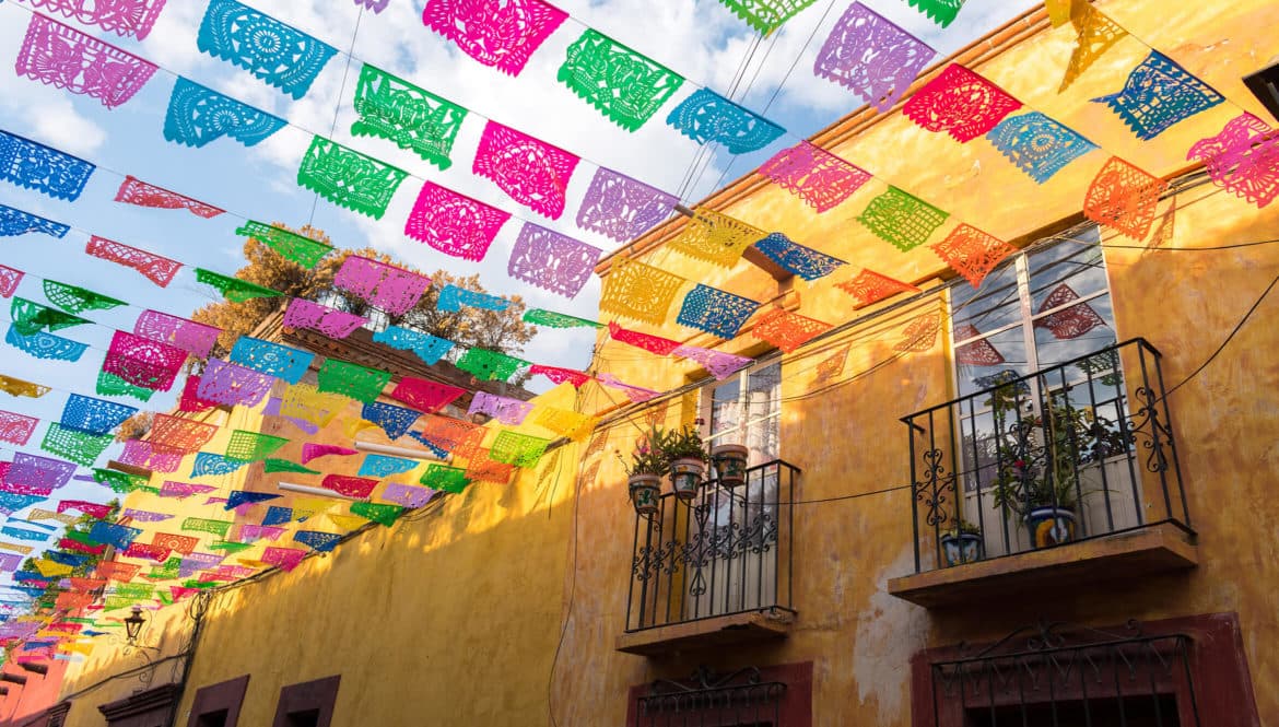 a building with a lot of colorful flags hanging from it's roof.