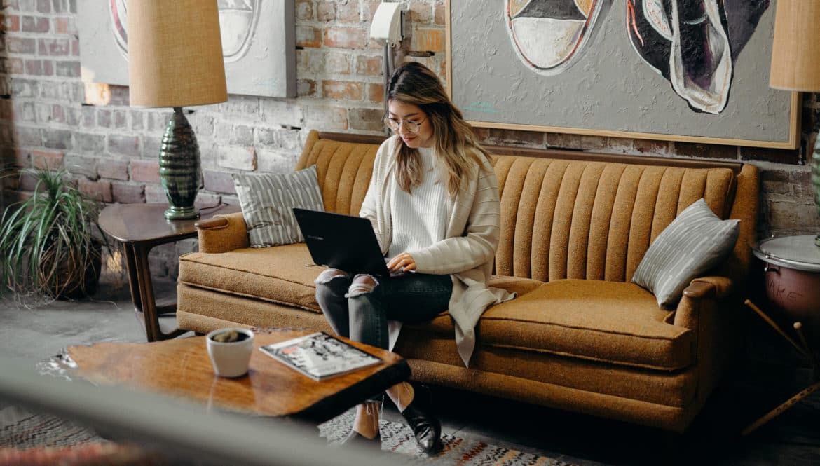 a woman sitting on a couch using a laptop.