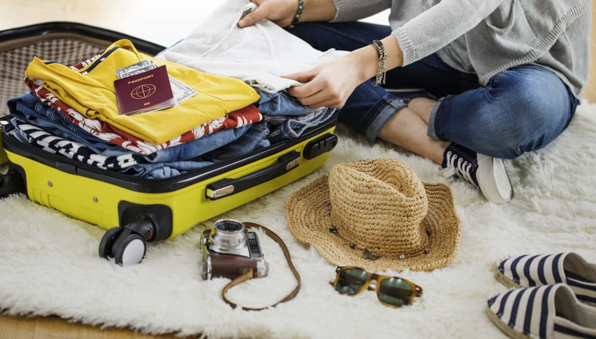 a woman packing her suitcase on a rug.