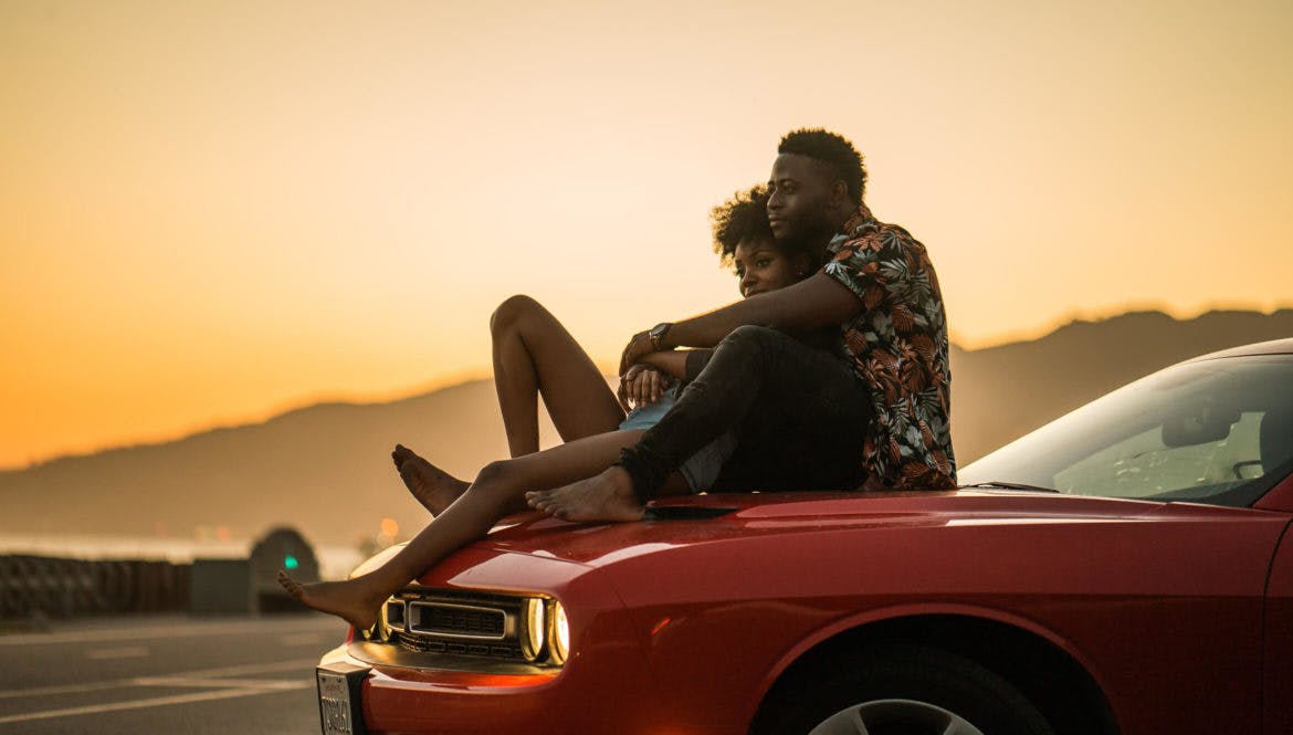 woman and man watching the sunset on the car