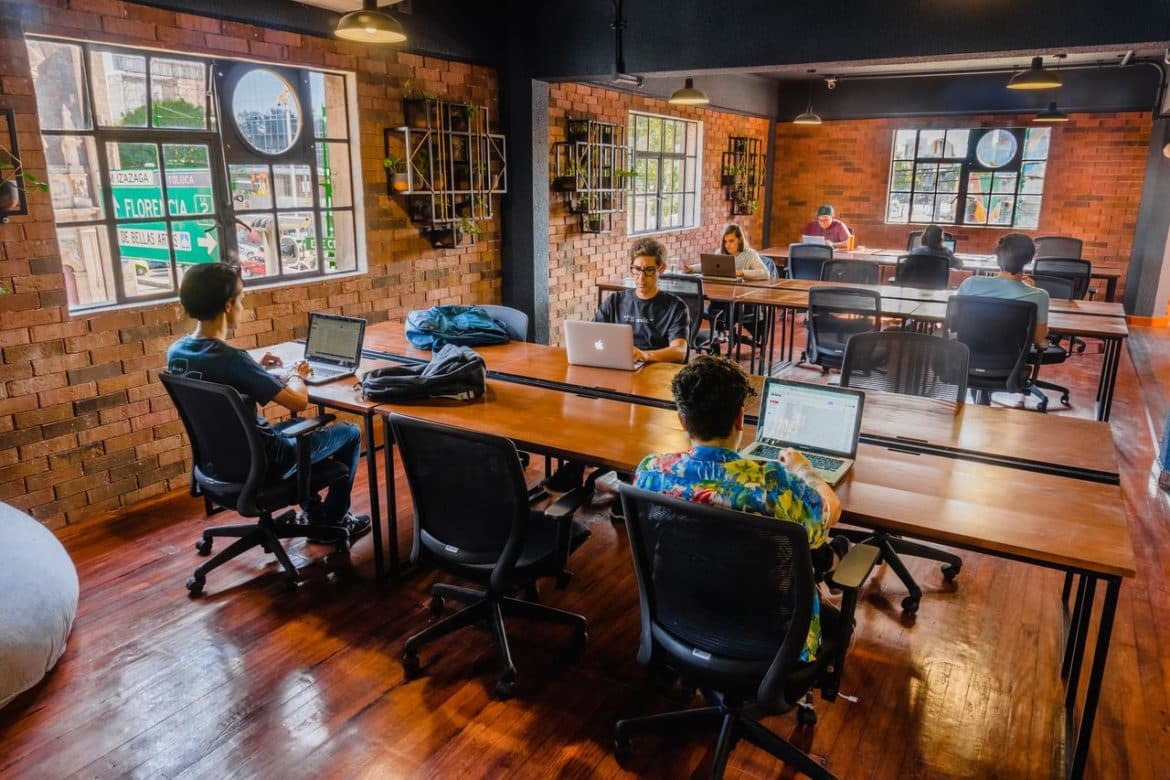 a group of people sitting at a table working on laptops.