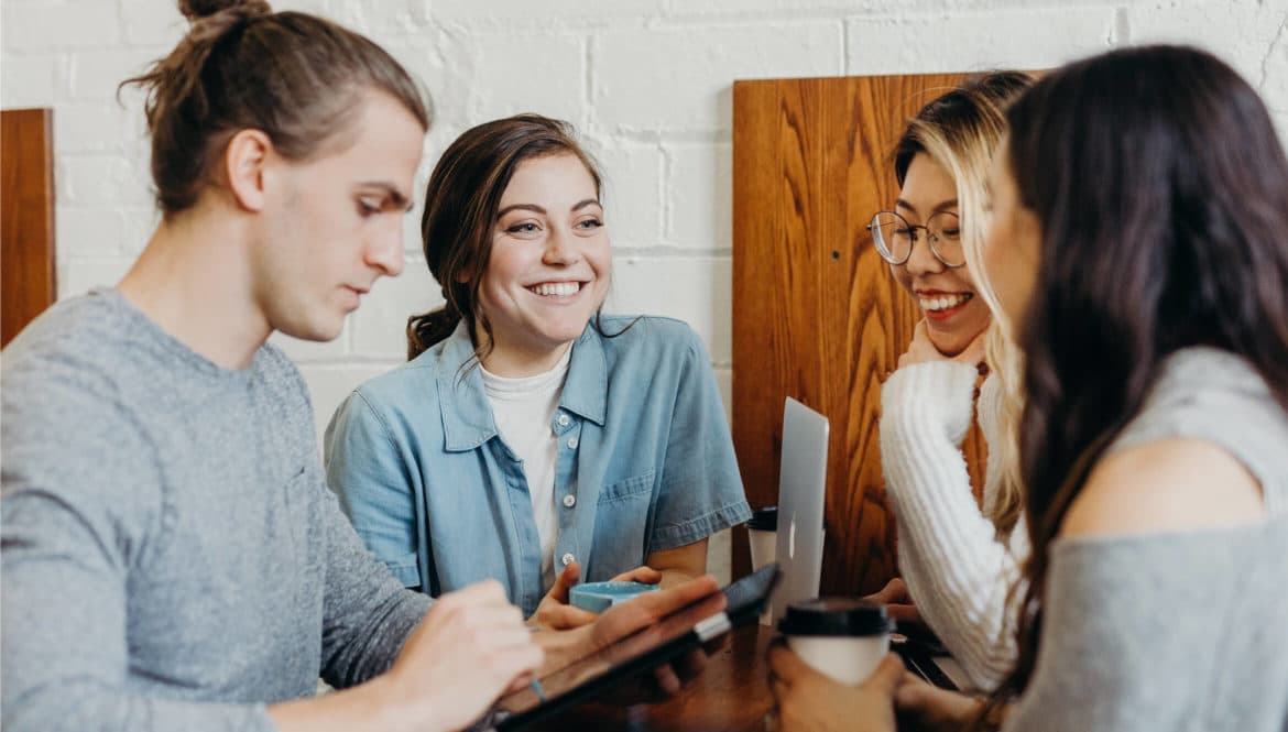 A group of people enjoying coliving spaces together around a wooden table.