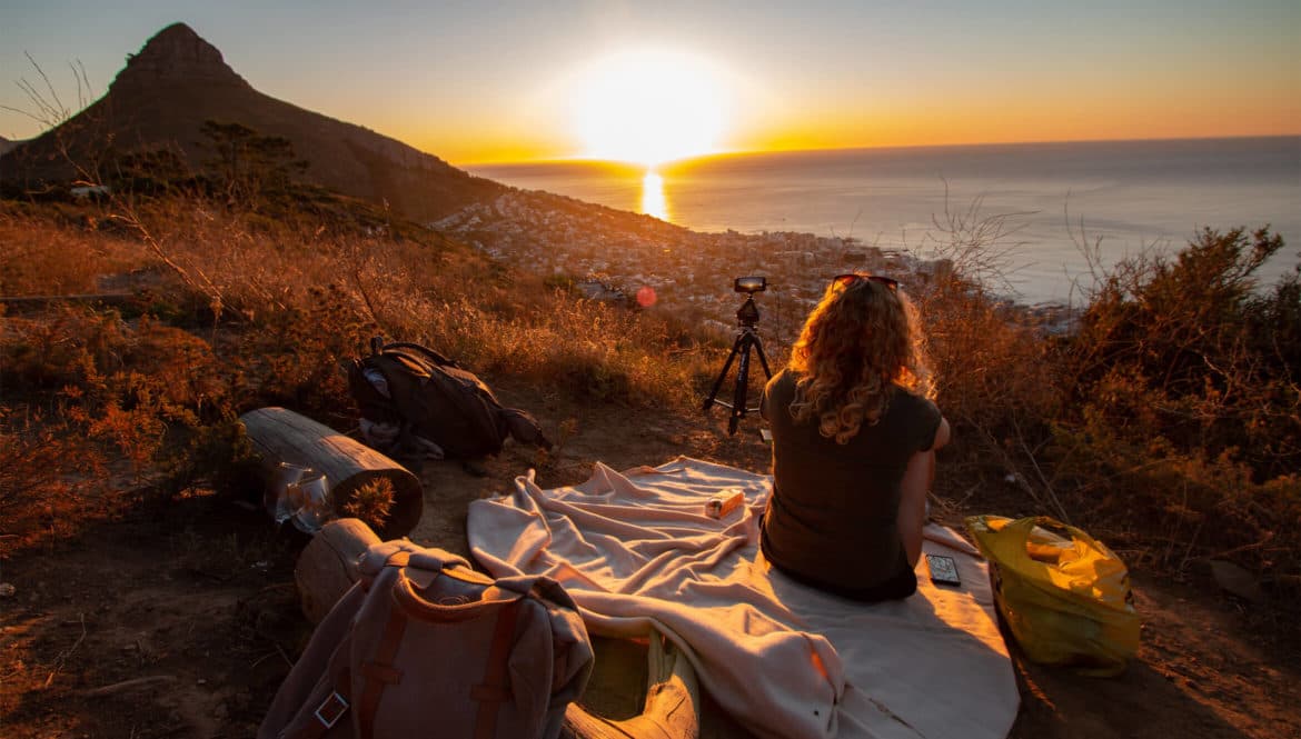 A woman enjoying the best workation destination on top of a hill with her bag.