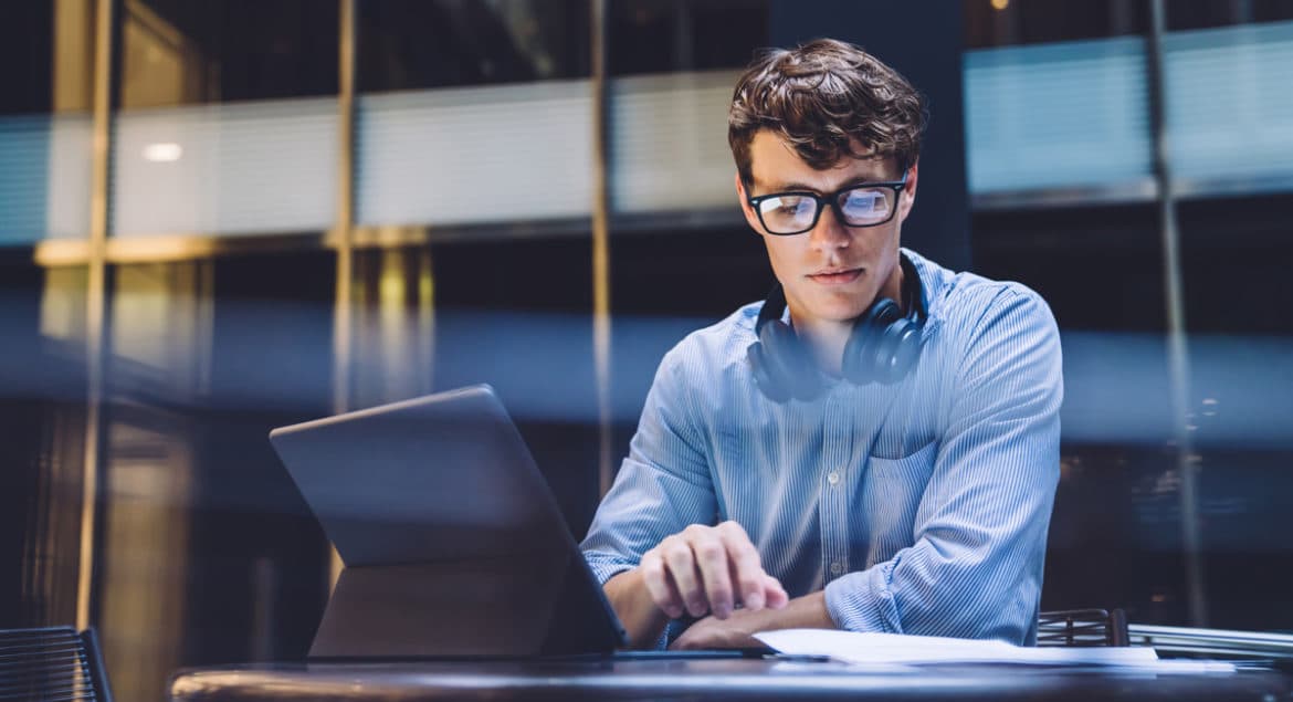 a man sitting at a table using a laptop computer.