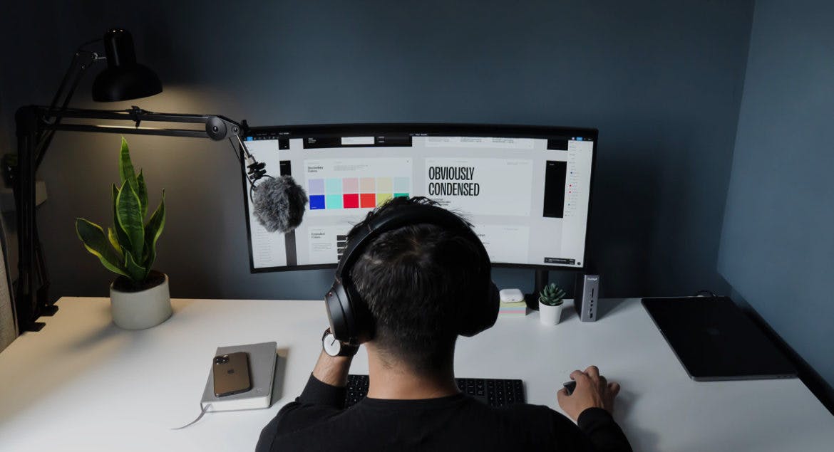 A man working remotely sits at his desk wearing headphones to improve productivity.