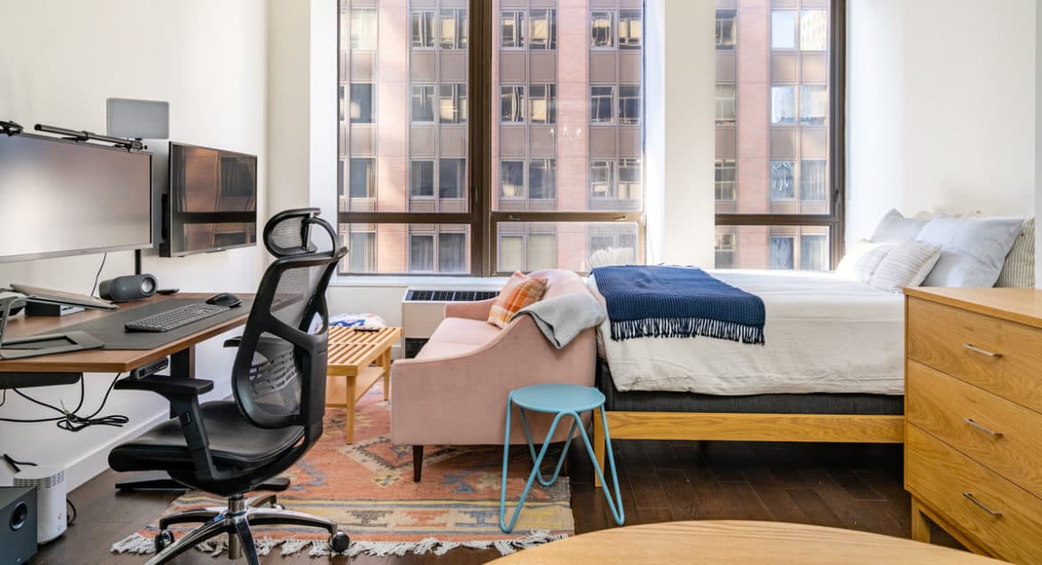 A relocated bedroom with a bed, desk, chair, and television.