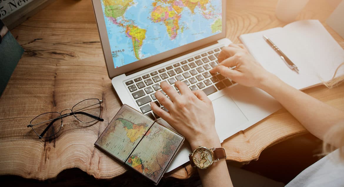 A woman working from anywhere using a laptop computer with a world map on the screen.