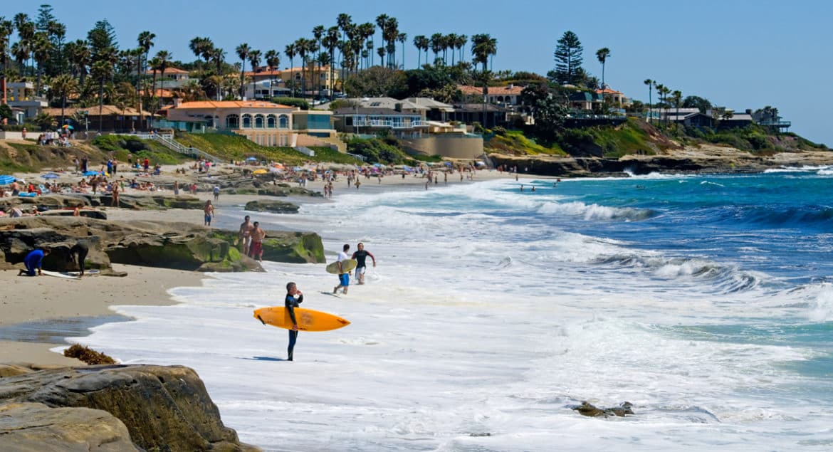 A workation group walking along a beach next to the ocean.