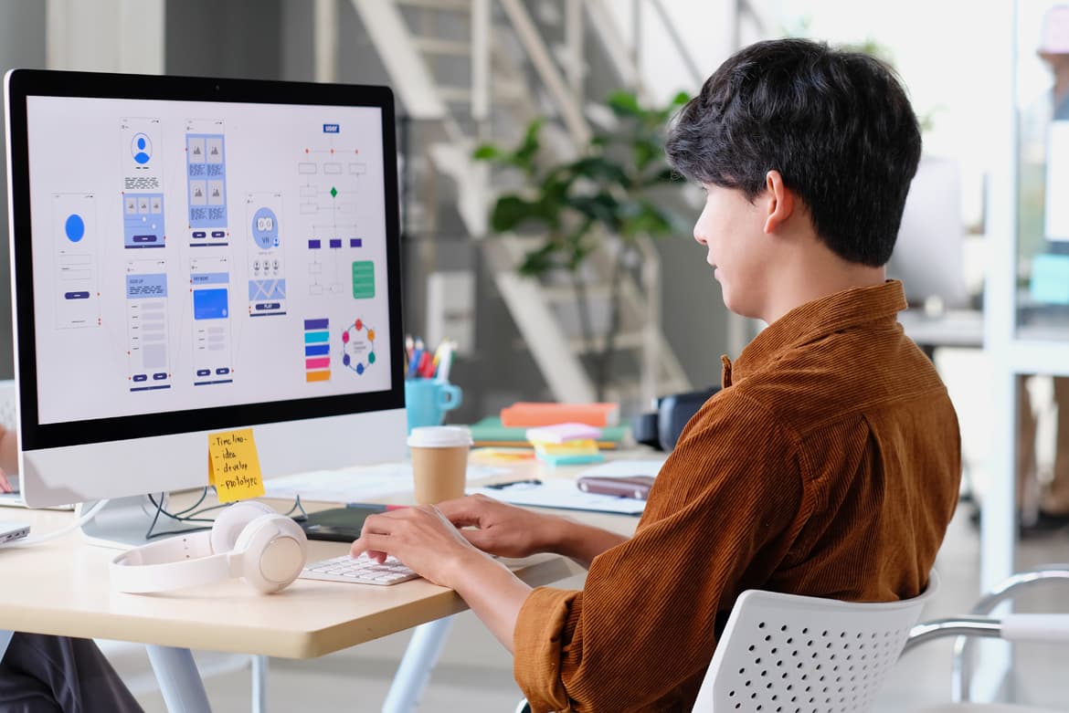 A man engaging in visual collaboration at a desk using a computer.