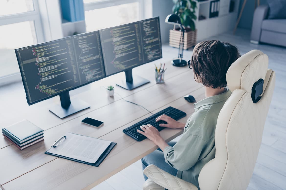 A person engaging in remote work at a desk with a keyboard and monitor.