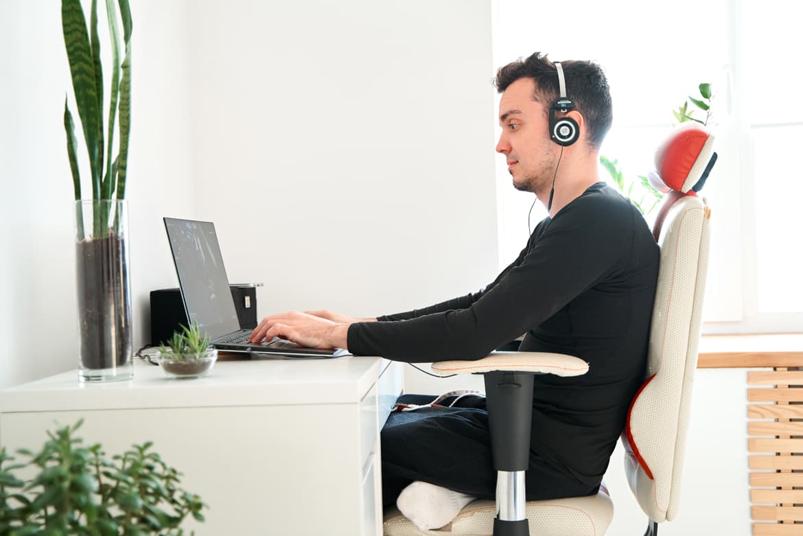 A man working remotely with a laptop and headphones, promoting wellness.