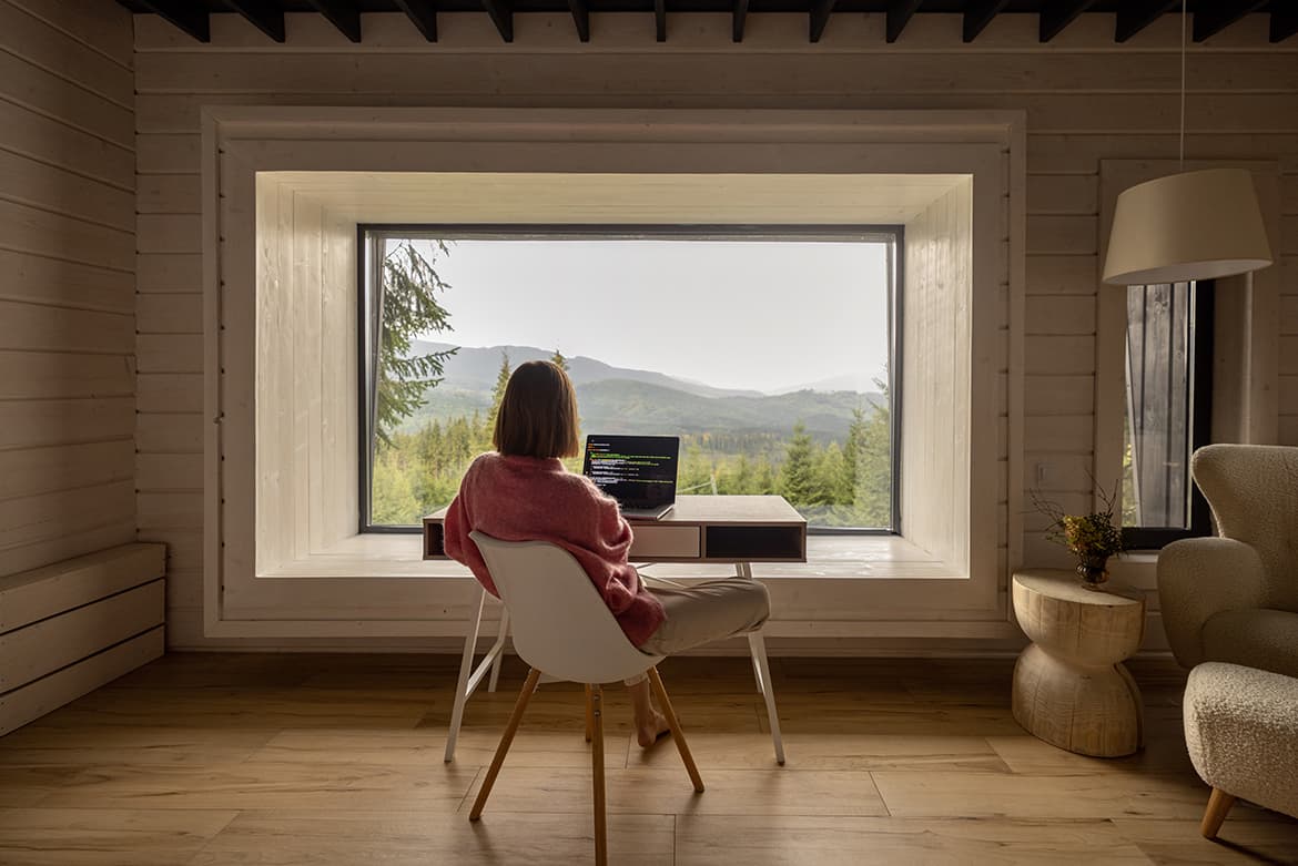 A woman on a workation sitting at a desk in front of a window.