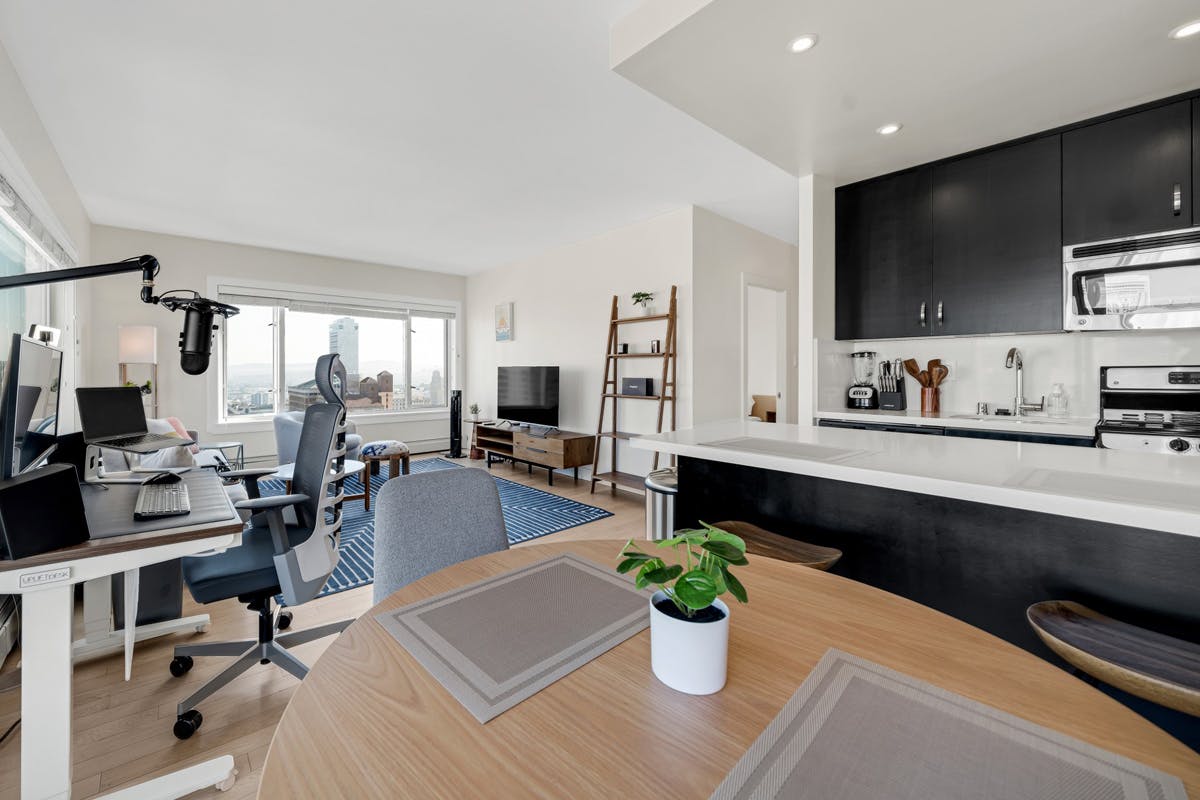 An executive apartment with a kitchen including a table, chairs and a television.