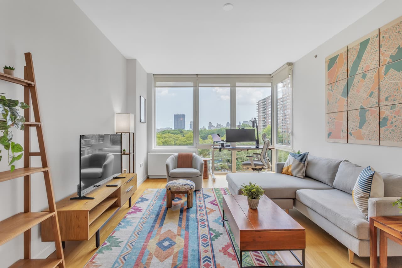 A furnished living room with large windows and a rug.